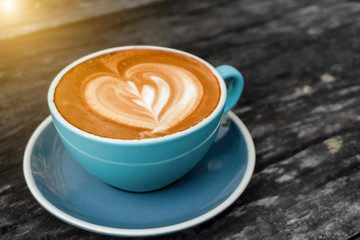 Coffee cup on old wood table with blur background of sunlight shining.