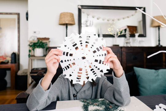 Young boy makes paper snowflakes