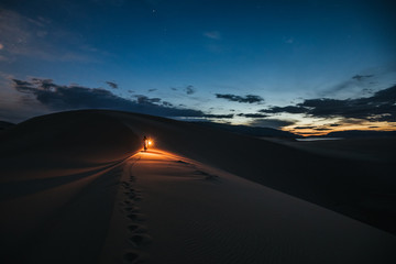 woman with lantern walking through the desert at night