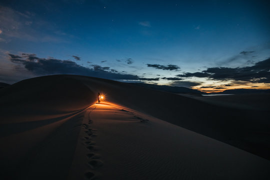 woman with lantern walking through the desert at night