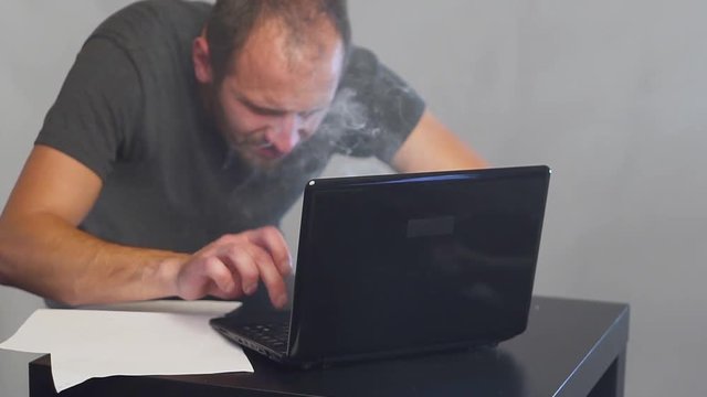 Crazy fanatical businessman working on a burning computer. Accountant report. Cryptocurrencies.