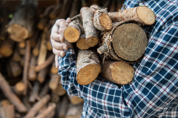 Man in plaid shirt carrying firewood