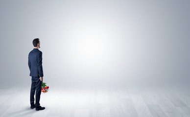 Man standing with his back in an empty room with object in his hand