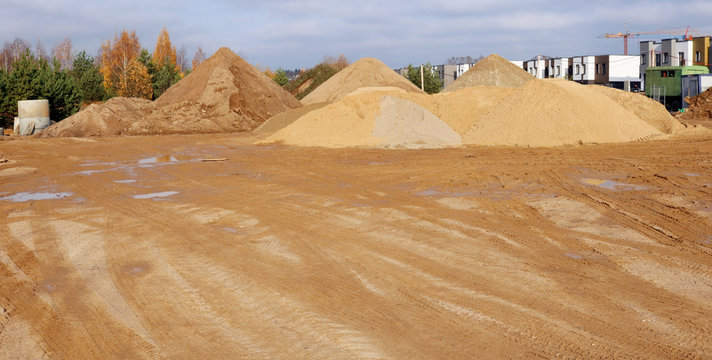 A large piles of construction sand with traces of tractor wheels on city building site