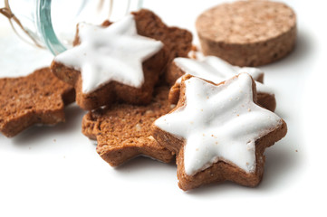 closeup of christmas biscuit in shaped star falling from glass container on white background