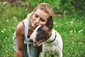 Girl on a green grass with bull terrier