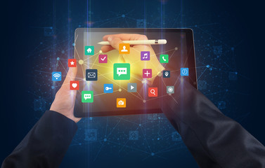 Hand using tablet with colorful bounce application symbols and icons concept
