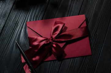 Red gift envelope decorated in a gentle romantic style on a black wooden background