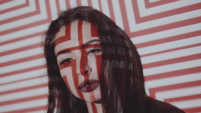 Portrait face of woman in lingerie and jacket posing with projected pattern on her. Music, nightclubs, shows and entertainment concept - video in slow motion