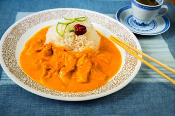 Chicken meat in spicy mango sauce with rice, chopsticks.