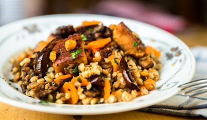 Chcickpeas and barley with fried vegetable on white plate.