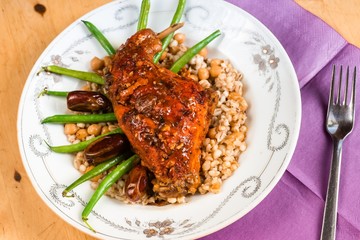 Rabbit leg, arley pearl and chickpeas, green bean on plate.
