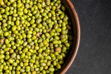 fresh mung beans in ceramic dishes against a dark stone background