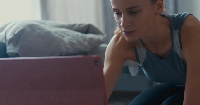 CU portrait of young attractive young woman taking online yoga classes at home, starting tutorial on her tablet pc. Healthy life, keep fit concepts. 4K UHD 60 FPS SLOW MOTION
