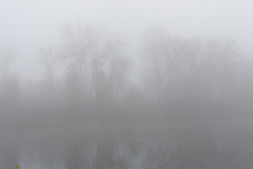 Fototapeta na wymiar Foggy condition of the autumn November weather on the river
