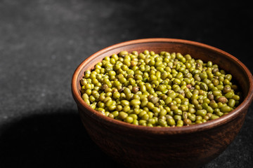fresh mung beans in ceramic dishes against a dark stone background
