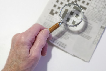 magnify glass used by elderly old senior poor sight and vision person for crossword puzzle