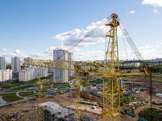 Naklejka premium Aerial drone view Cranes close-up on construction site against blue sky
