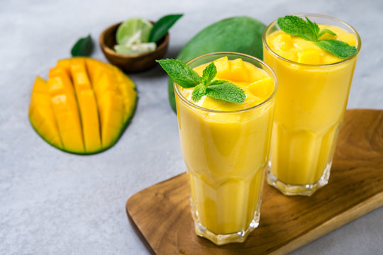 Fresh mango juice and mango fruit on grey background