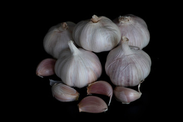 garlic on black background , dark tone, some clove garlic are seperated. Garlic is a plant in the Allium (onion) family. The active ingredients of garlic are alliinase, alliin , allicin