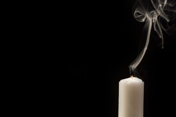 Kerze mit erloschener Flamme vor schwarzem Hintergrund