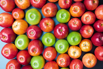 heap of green and red apples mix on blue background, top view flat lay