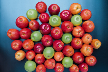 heap of green and red apples mix on blue background, top view flat lay