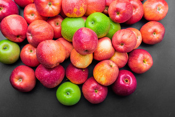 heap of fresh clean green and red apples with drops of water mix on black background, top side view closeup