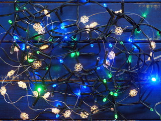 Bright Christmas background - colored garland on blue wooden background