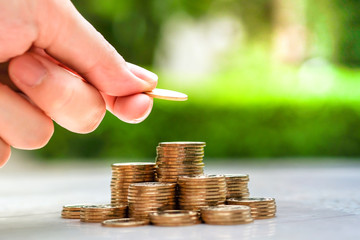 Hand putting coin to stack of coins. Business and Finance, Saving money for future or retirement,...