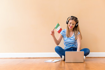 Young woman with Italian flag using a laptop computer against a big interior wall