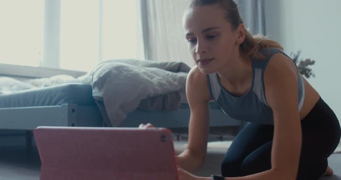 CU portrait of young attractive young woman taking online yoga classes at home, starting tutorial on her tablet pc. Healthy life, keep fit concepts. 4K UHD 60 FPS SLOW MOTION