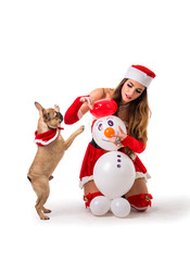 Pretty young woman in Santa Claus hat and costume, with pug dog, kneeling holding colorful festive Christmas gifts to celebrate the season, on white background