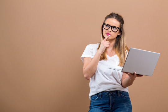 Young woman with a laptop computer in a thoughtful pose on a brown background