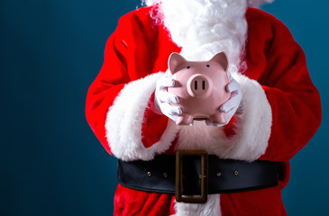 Santa holding a piggy bank on a dark blue background