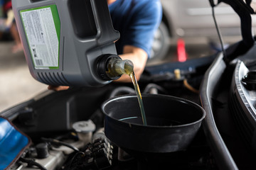 Car mechanic fills a fresh lubricant engine oil