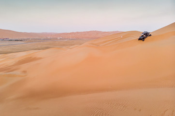 Fototapeta na wymiar aeril view of Liwa desert, dune buggy driving down a dune