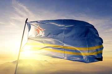 Aruba Arubian flag textile cloth fabric waving on the top sunrise mist fog