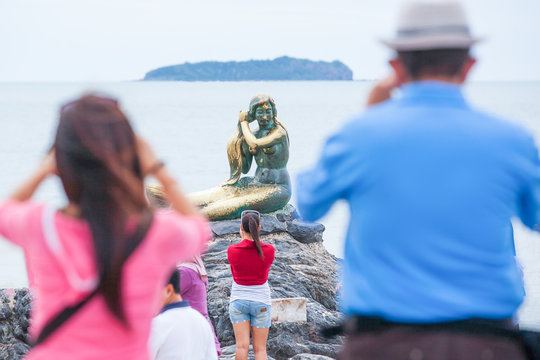 Tourists taking pictures the Mermaid statue symbol on the beach.