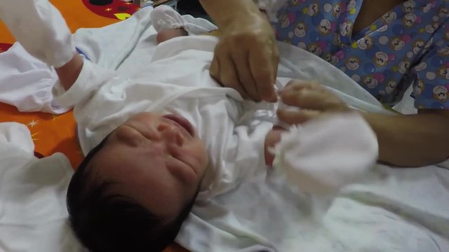 nurse undresses infant boy during pediatric medical checkup