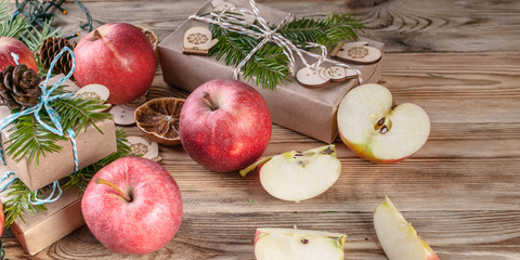 Web banner Christmas background. Red apples, gifts, fir branches and cones on a wooden background