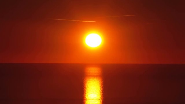 Sunset over the sea. Red big Sun sets over the horizon. Path of sunlight on the water
