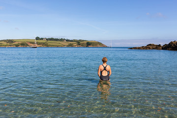 Female swimmer entering the water at Helford River Estuary in Cornwall, England.