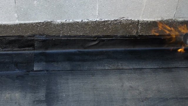 Worker preparing part of bitumen roofing felt roll