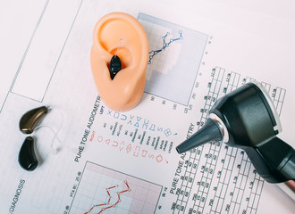 Hearing exam result - audiogram and hearing aids on the table