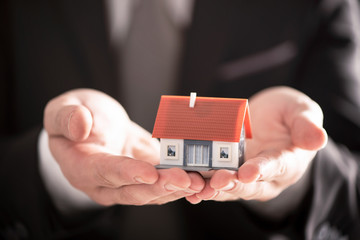 Businessman hand holding an house model