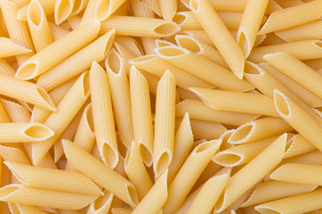 Pennoni uncooked whole wheat penne pasta, top view. Food background.