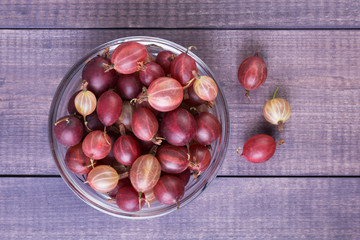 Heap of red and yellow gooseberry in a bowl on wooden background. Fresh delicious berries on  boards. Top view