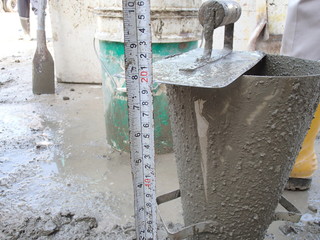 Construction workers doing slump test using specific equipment at the construction site. Witness by...