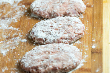 Raw cutlets of minced meat on the cutting Board. Sprinkle with flour.